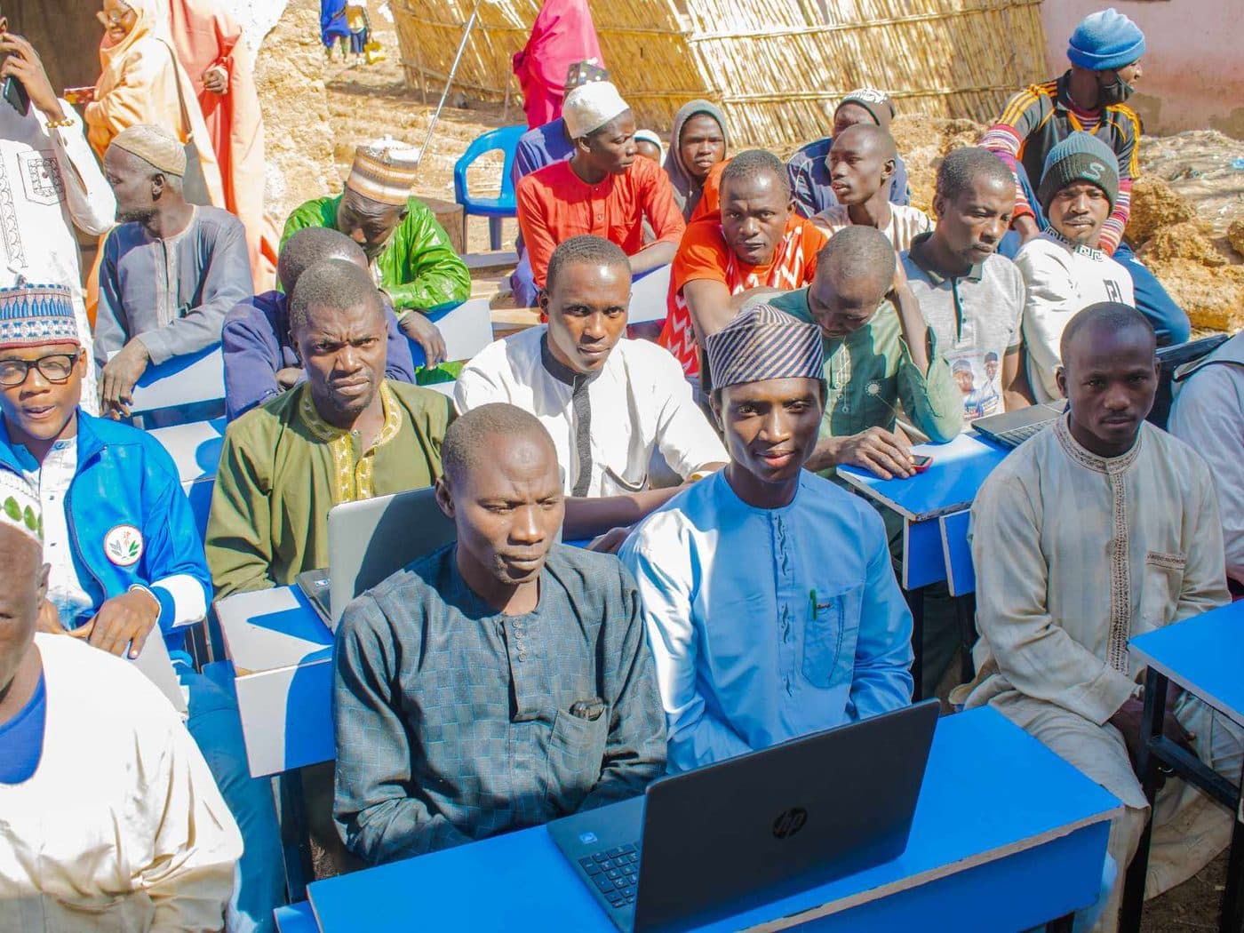 Community members seated at classroom desks working on laptops during a session